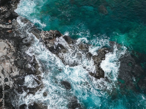 waves hitting rocks and cliffs in the sea, viewed from above