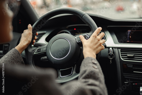 Back view of woman driver pushes the button on steering wheel during drive photo
