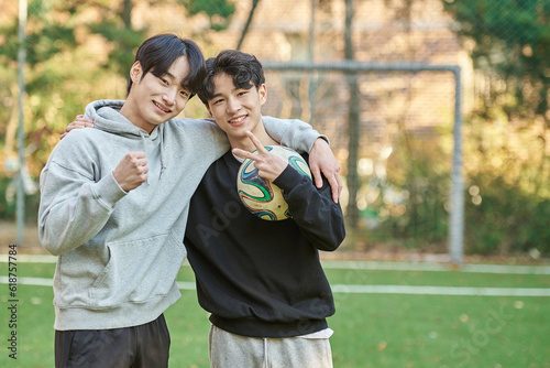 Young male college students pose for a post-match shoulder rub at a university futsal field in South Korea, Asia