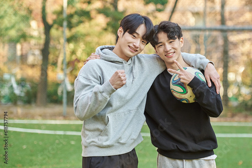 Young male college students pose for a post-match shoulder rub at a university futsal field in South Korea, Asia photo