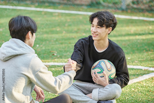 Young male college students pose for a post-match shoulder rub at a university futsal field in South Korea, Asia