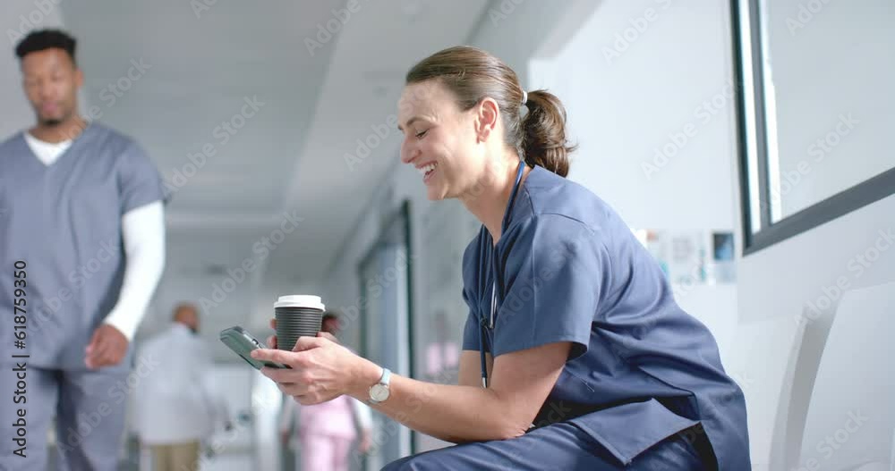 Caucasian female doctor using smartphone and drinking coffee in corridor, copy space, slow motion Caucasian female doctor using smartphone and drinking coffee in corridor, copy space, slow motion