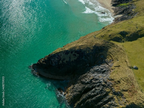 an aerial view of the ocean and a sandy shore with a green island