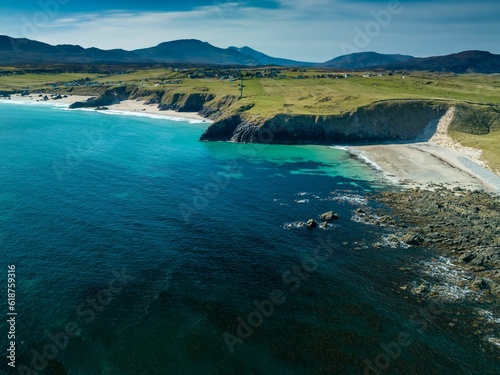 an aerial view of a sandy beach and blue waters with grass on either side