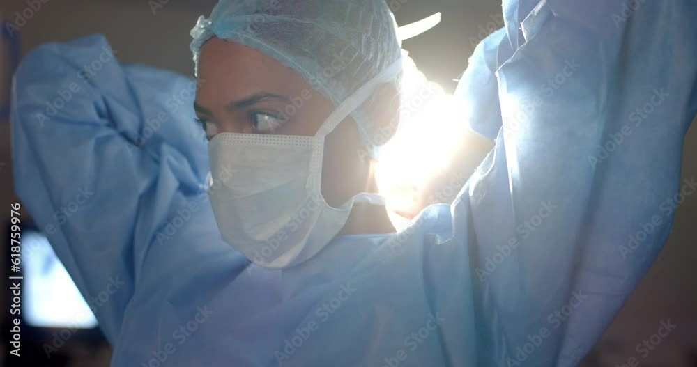 Biracial female surgeon wearing face mask in operating theatre, slow motion
