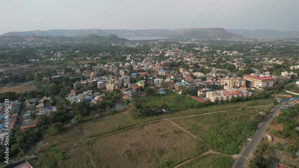 Descending drone over lawn fields with traditional city houses roofs with blue sky Descending drone over lawn fields with traditional city houses roofs with blue sky