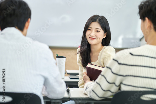 Male and female university students looking backwards talking or discussing during class or studying in a lecture hall at a Korean university in Asia.