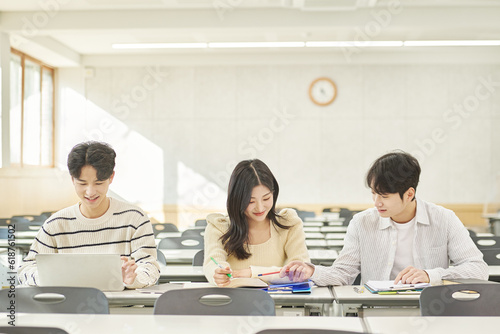 Three young Asian college students  both male and female  are in a classroom in South Korea where they are either teaching or studying