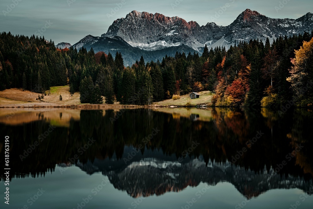 Scenic view of a tranquil lake surrounded by green trees and snowy mountains in Bavaria, Germany