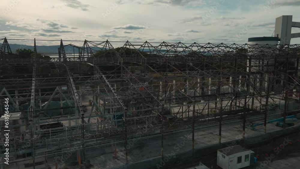Aerial view of an abandoned industrial structure with cranes near a river with sunset cloudy sky Aerial view of an abandoned industrial structure with cranes near a river with sunset cloudy sky