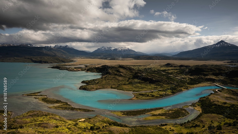 Obraz premium Scenic view of a lake surrounded by green mountains on a cloudy day
