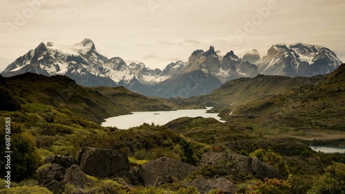 Fototapeta Naklejka Na Ścianę i Meble -  Scenic view of a lake surrounded by green mountains on a cloudy day
