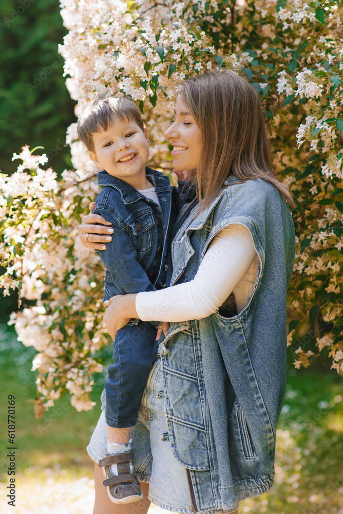 Fototapeta premium Caucasian family, mom and little son hug and have fun on a walk in the park in summer. Mother's Day