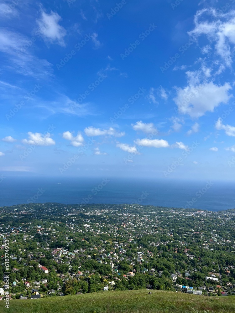 Aerial view of an island surrounded by crystal blue ocean water and white fluffy clouds in the sky