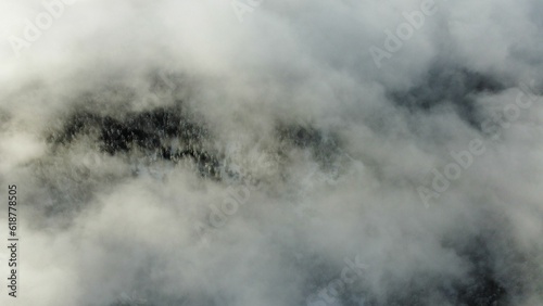 Top view of the clouds over the mountains with dense trees