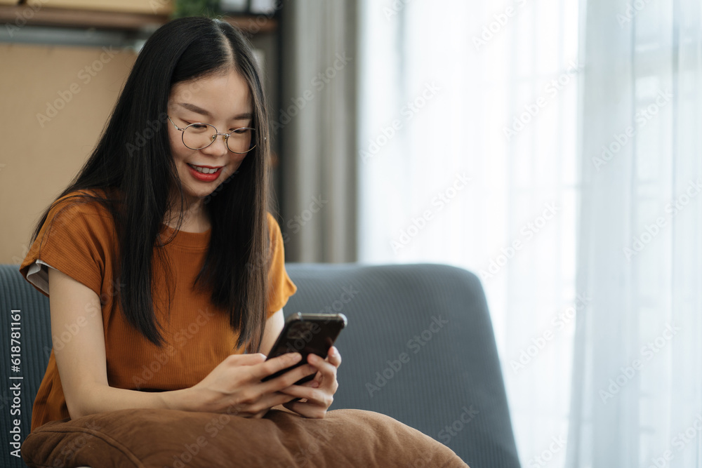 young asian woman using mobile phone surfing the internet, searching information during online working on laptop computer at home office. young asian woman using mobile phone surfing the internet, searching information during online working on laptop computer at home office.