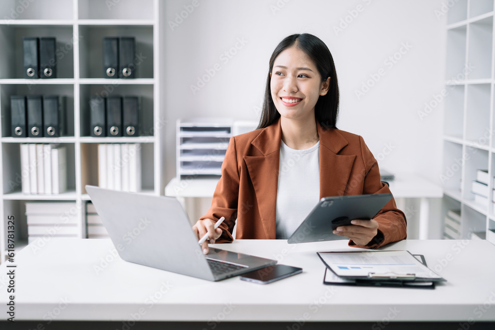 Cropped view of smiling beautiful woman writing in a journal while sitting at desk in office. Cropped view of smiling beautiful woman writing in a journal while sitting at desk in office.