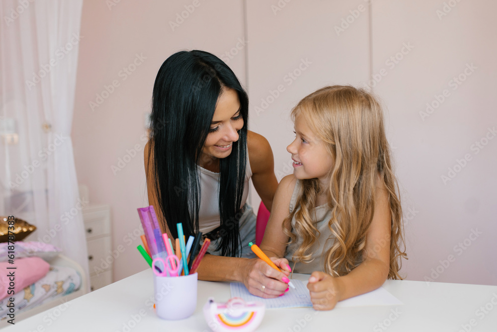 Mother helps her adorable daughter with homework Mother helps her adorable daughter with homework