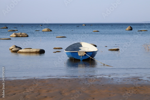 Blue lonely boat in calm sea near the shore. Amazing sunset in summer evening. photo