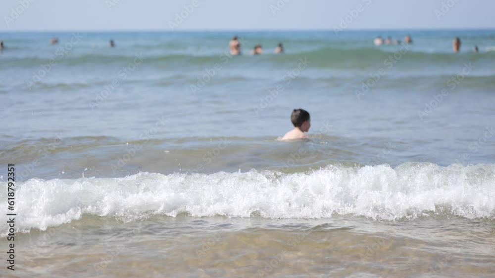 Happy child playing in the sea. Kid having fun outdoors. Summer vacation and holiday concept. Slow motion Happy child playing in the sea. Kid having fun outdoors. Summer vacation and holiday concept. Slow motion
