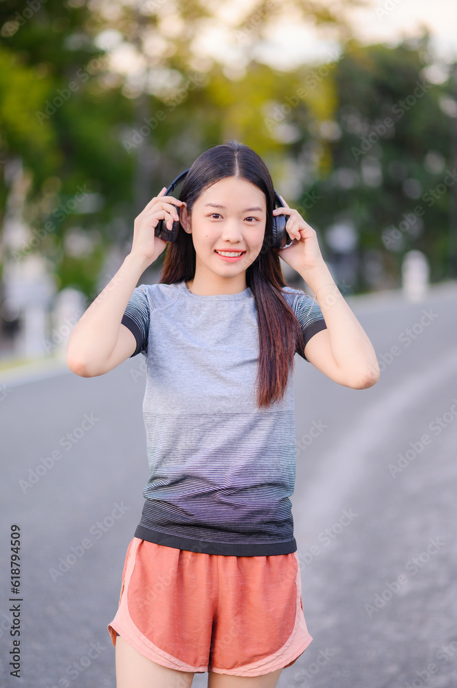 attractive asian woman healthy jogging exercise with headphones  in park outdoor at evening