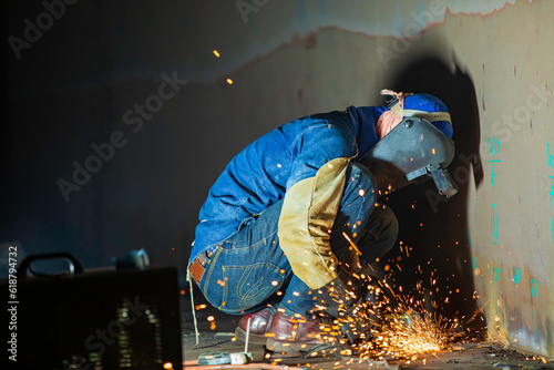 Male worker grinding on steel plate with flash of sparks close up wear protective gloves oil inside