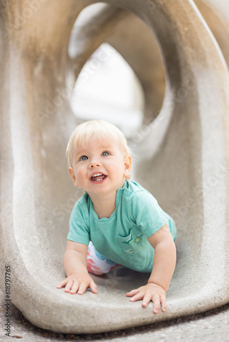 Child playing on outdoor playground. Toddler plays on school or kindergarten yard. Active kid on stone sculpured slide. Healthy summer activity for children. Little boy climbing outdoors photo