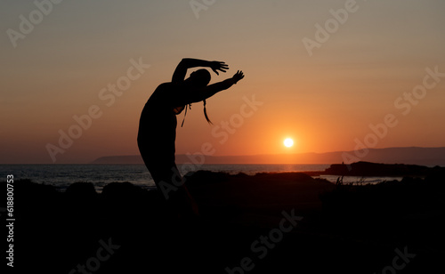 Woman doing yoga at a sandy beach at sunset. Caucasian woman meditating outdoors at the coast
