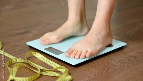 Wallpaper Mural White floor scales and women's feet standing on them. A tailor's centimeter or measuring tape lying nearby to measure body changes. The concept of a healthy lifestyle and body weight tracking Torontodigital.ca