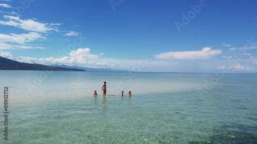 Three triplet sisters with their mother on a sand spit in the ocean twins photo