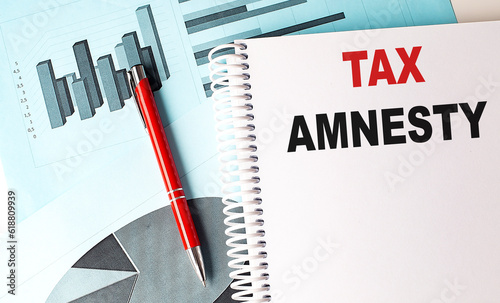 TAX AMNESTY text on a notebook with pen on a chart background photo