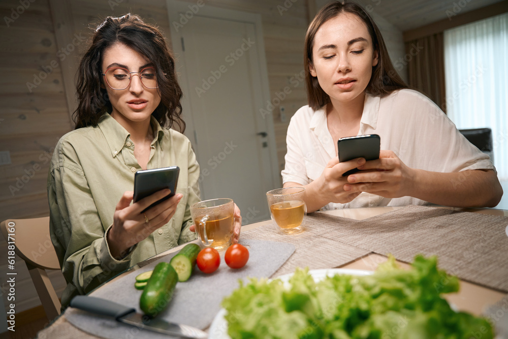 Young women drink tea and using phones