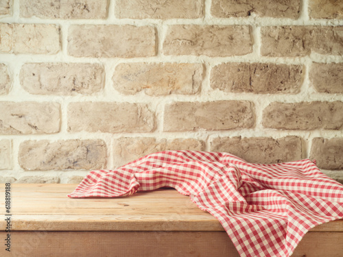 Empty wooden table with tablecloth over brick wall background. Kitchen mock up for design and product display