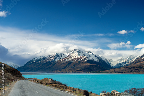 Scenic view at Mount Cook Road alongside Lake Pukaki with snow capped Southern Alps basking in the late winter evening light. Best road trip route in New Zealand South Island.