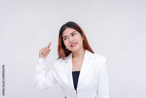 A confused young woman pointing on her brain trying to think of ideas. Isolated on a white background.
