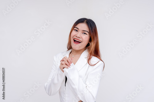 An optimistic young woman with hands clasped together in excitement. Isolated on a white background.