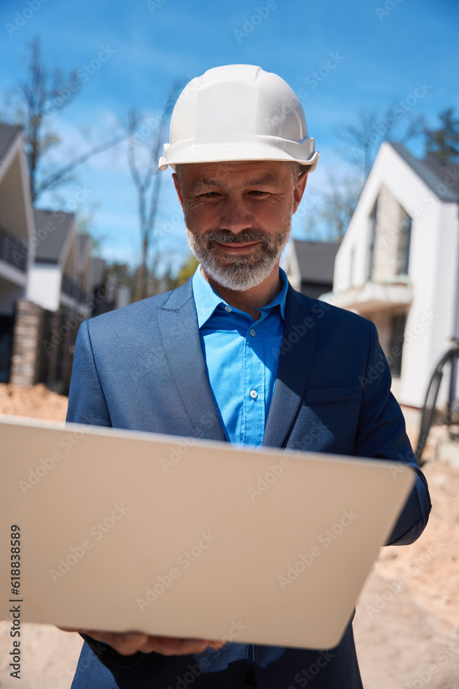 Male geodesist checking landscape and lie of ground using laptop Male geodesist checking landscape and lie of ground using laptop