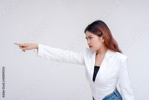 An irked and irritable young woman glaring and pointing to the left. Isolated on a white background.