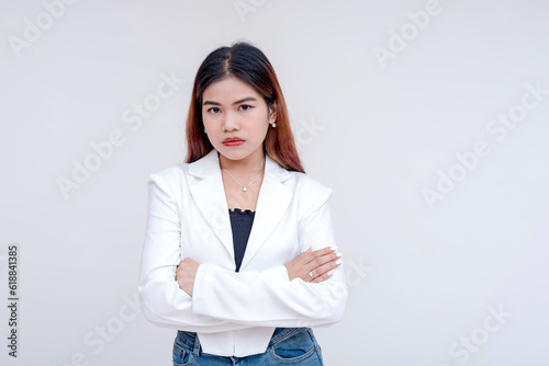 An irked and irritable young woman glaring at the camera with arms crossed. Isolated on a white background. photo