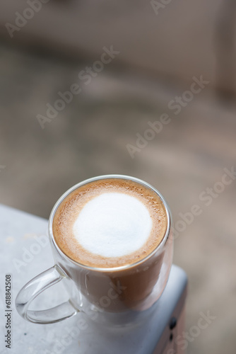 A cup of hot latte on cement table.