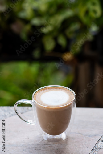 A cup of hot latte on cement table.