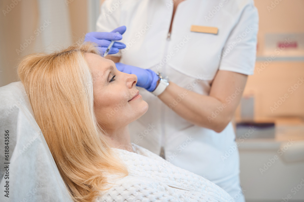 Close up of adult lady getting antiwrinkle injection at cosmetologist Close up of adult lady getting antiwrinkle injection at cosmetologist