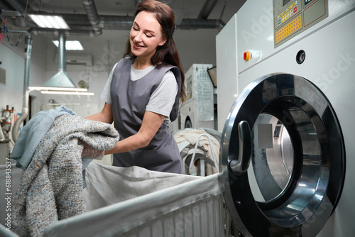 Obraz na płótnie Dry cleaning service worker loading industrial washing machine with clothes w salonie