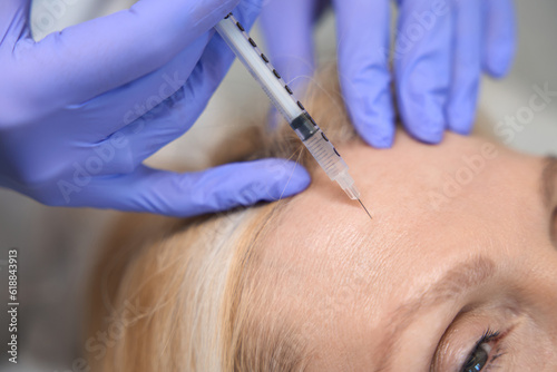 Close up of adult lady getting antiwrinkle forehead injection photo