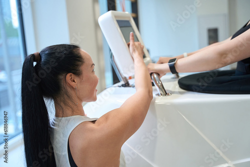 Young trainer and client of clinic communicate in fitness room