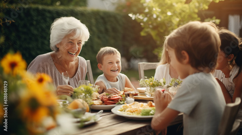 Happy Senior Grandmother Talking and Having Fun with Her Grandchildren  Outdoors Dinner with Food and Drinks. Adults at a Garden Party Together with Kids.