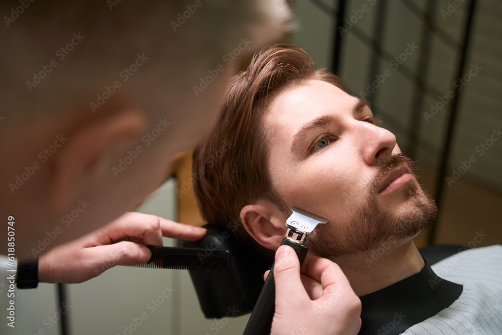 Master barber works with a young client in a barbershop Master barber works with a young client in a barbershop