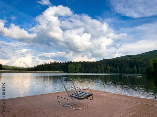 Rocking chair on a wooden pontoon near the lake on a cloudy summer day