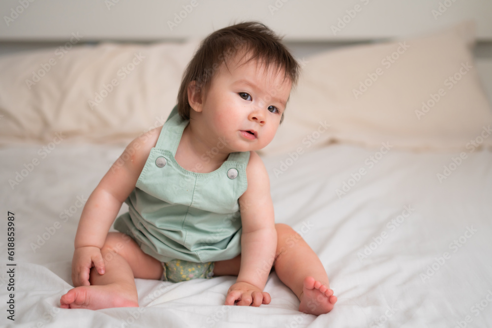 Mixed ethnicity Asian Caucasian 8 months baby girl - lifestyle home portrait of adorable and happy female child lying playful on bed exploring the surroundings curious Mixed ethnicity Asian Caucasian 8 months baby girl - lifestyle home portrait of adorable and happy female child lying playful on bed exploring the surroundings curious