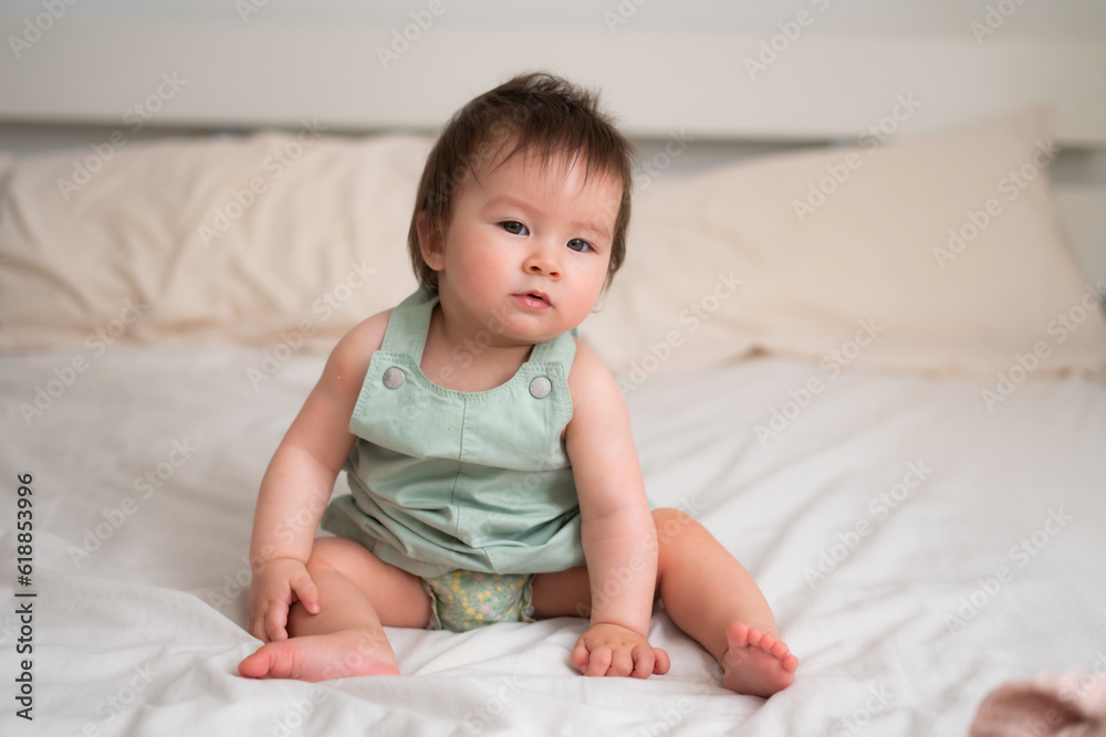Mixed ethnicity Asian Caucasian 8 months baby girl - lifestyle home portrait of adorable and happy female child lying playful on bed exploring the surroundings curious Mixed ethnicity Asian Caucasian 8 months baby girl - lifestyle home portrait of adorable and happy female child lying playful on bed exploring the surroundings curious